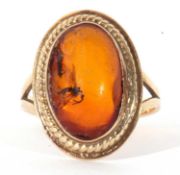 14k stamped amber ring, the oval cabochon shaped amber centre stone bezel set in a rope twist