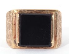 9ct gold and onyx ring, the square black onyx panel 10 x 10mm, raised between textured shoulders,