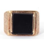 9ct gold and onyx ring, the square black onyx panel 10 x 10mm, raised between textured shoulders,