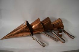 GRADUATED GROUP OF FOUR COPPER FUNNEL FORMED ALE WARMERS TOGETHER WITH A FURTHER SMALL COPPER JUG (