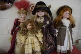 FOUR VARIOUS MODERN PORCELAIN HEADED COLLECTORS DOLLS ON STANDS