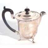 George V silver teapot of circular form having a hinged lid with an ebonised urn finial and scroll