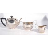 George V silver three piece tea set of oval form with half fluted bodies comprising teapot, sucriere