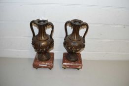PAIR OF CONTINENTAL BRONZED METAL DOUBLE HANDLED VASES SET ON POLISHED MARBLE BASES