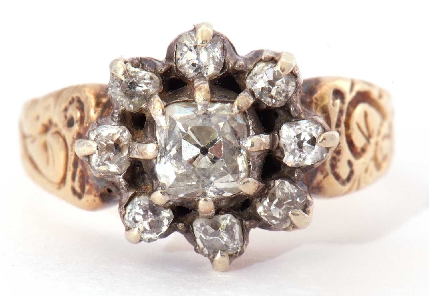 Diamond cluster ring centering an old cushion cut diamond surrounded by seven small old cut diamonds