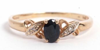 Modern 9ct gold dark sapphire and diamond ring, the oval shape faceted sapphire raised between small