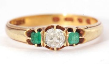 18ct gold diamond and emerald ring centering an old cut diamond, 0.25ct app, raised between two