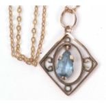 Open work pendant suspending a pear shaped blue stone dropper suspended from a 375 stamped chain