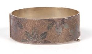 A silver hallmarked hinged bracelet, the top section chased and engraved with a floral design,