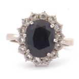 18ct white gold, dark sapphire and diamond ring, the oval faceted sapphire is 10x8mm, raised above a