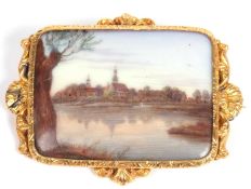 Antique hand painted porcelain brooch depicting a village and wooded river scene, 4x3cm, in a high