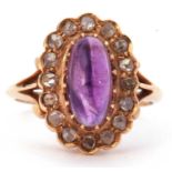 Amethyst and diamond cluster ring centering an oval cabochon cut amethyst, multiclaw set within a