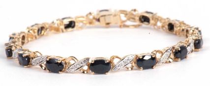 Modern sapphire and diamond bracelet featuring fourteen oval dark sapphires joined by a single stone