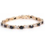 Modern sapphire and diamond bracelet featuring fourteen oval dark sapphires joined by a single stone