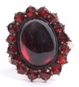 Bohemian style garnet cluster ring, the central cabochon surrounded by faceted smaller stones,