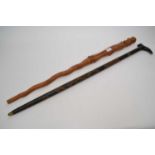 Ebonised wooden sword stick with a carved design together with a further walking stick with a carved