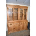 Modern pine kitchen dresser with four glazed doors over a base with four drawers and four doors,