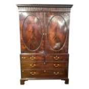 George III mahogany linen press cabinet with moulded cornice over two oval panelled doors and a four