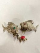 Two white metal models of fish and a small pin cushion modelled as a rabbit