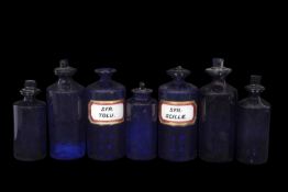 Group of large coloured glass, mainly blue glass, chemist jars some with content labels, most with