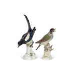 Two meissen models of birds including a magpie and a woodpecker, both on branches with flowers, blue