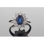 Sapphire and diamond cluster ring, the oval sapphire set within a round brilliant cut diamond