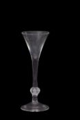 A wine glass with the trumpet bowl above a clear stem with basal knop and folded foot, 19cm high