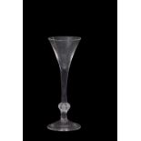 A wine glass with the trumpet bowl above a clear stem with basal knop and folded foot, 19cm high