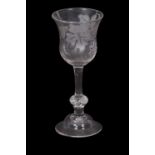 A wine glass engraved with leaves and a fruiting vine and butterflies above a clear stem and a basal
