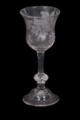 A wine glass engraved with leaves and a fruiting vine and butterflies above a clear stem and a basal