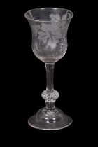A wine glass engraved with leaves and a fruiting vine and butterflies above a clear stem and a basal