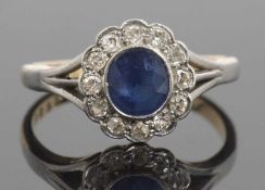 18ct gold sapphire and diamond cluster ring, the oval cut faceted sapphire bezel set within a