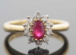 18ct gold ruby and diamond cluster ring, the oval faceted shaped ruby raised above a diamond