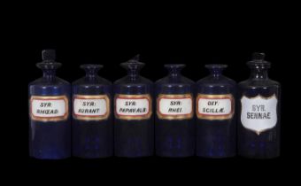 Group of six blue glass drug jars, some with stoppers with labels, tallest 24cm