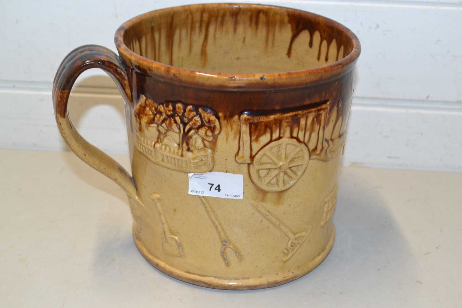 Large treacle glazed tankard decorated with various sprigs of country scenes, farm implements etc
