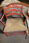 A rush seated ladder back armchair with red painted frame