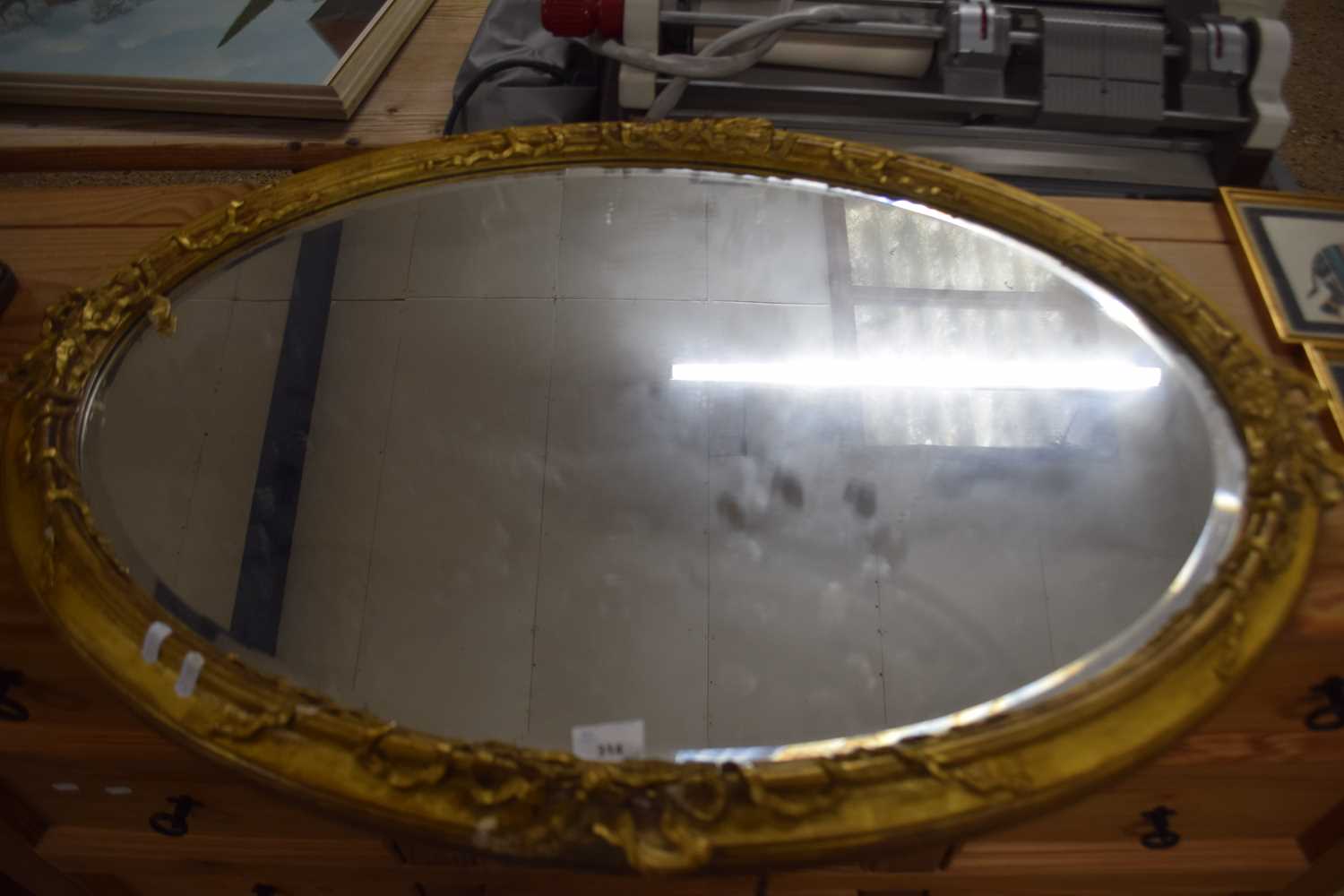 19th Century oval bevelled wall mirror in gilt finish frame with ribbon decoration