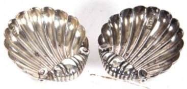 A small pair of late Victorian shell formed salts on three ball feet, 5cm wide, London 1894 by