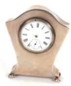 Edwardian silver encased dressing table clock with watch movement standing on four cheese feet (