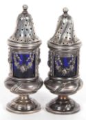 A pair of continental urn shaped peppers, the pierced covers with ball finials, the bodies decorated