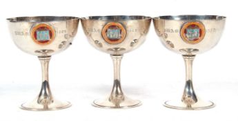 Three George V silver goblets, each applied with a circular enamel plaque, Commune Inhabitancium