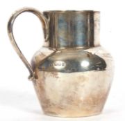 George V milk jug of plain circular baluster form, looped handle, 11cm tall, London 1919, probably