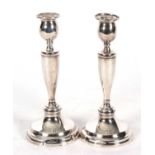 A pair of George V silver candlesticks with loaded circular bases, vase shaped stems, baluster