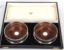 Cased pair of modern circular coasters with treen and silver centered inners, plain polished