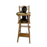 A vintage plastic baby doll with gold hoop earrings in wooden high-chair.
