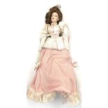 A porcelain doll on stand, formed as a Victorian lady in pink dress and floral jacket. Height