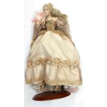 A porcelain doll on stand, formed as a lady in masquerade ball gown, with feathered face mask and