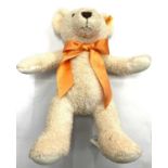 A 2015 Steiff teddy bear: 38 Creme Cosy Year. With orange bow and gold Steiff rivet and label to