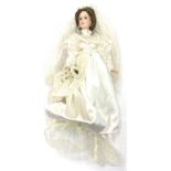 A porcelain doll formed as a bride, in white gown with lace veil and floral bouquet. height