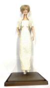 A porcelain doll on stand, modelled as the late Diana, Princess of Wales.Height approximately 44cm